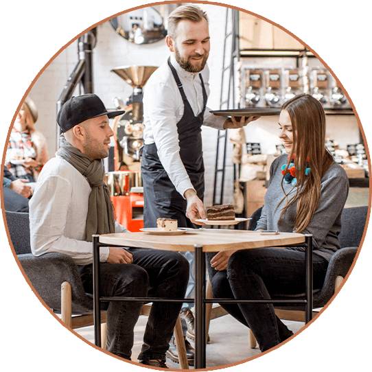 Two people being served by a waiter in a cafe